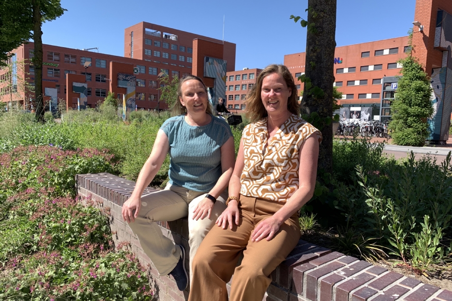 Beleidsadviseur groen Annemieke Feijen (rechts) poseert samen met Marit Benning, beheeradviseur groen voor de bestaande stad, voor de recentelijk heringerichte groenstrook naast het stadskantoor: 'Hopelijk kunnen deze bomen nu echt gaan groeien!'